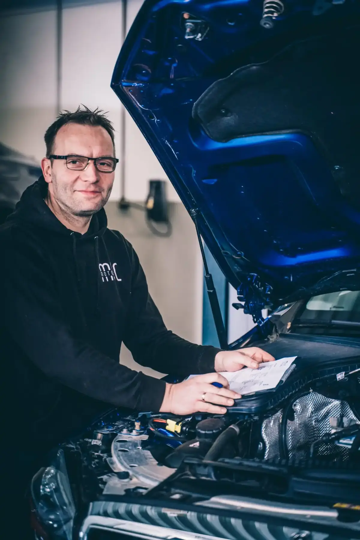 Mechaniker von MUC Motors prüft den Motorraum eines Fahrzeugs