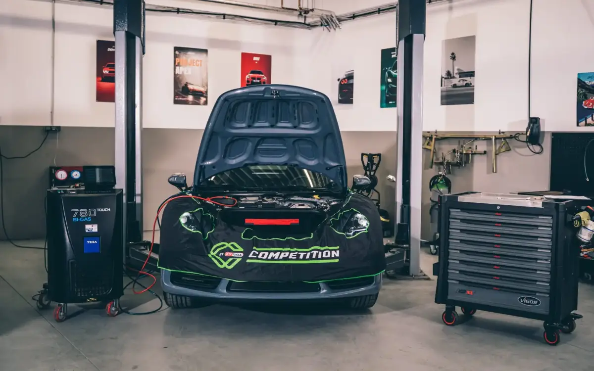 Fahrzeug mit geöffneter Motorhaube neben dem Klimaservicegerät in der MUC Motors Werkstatt